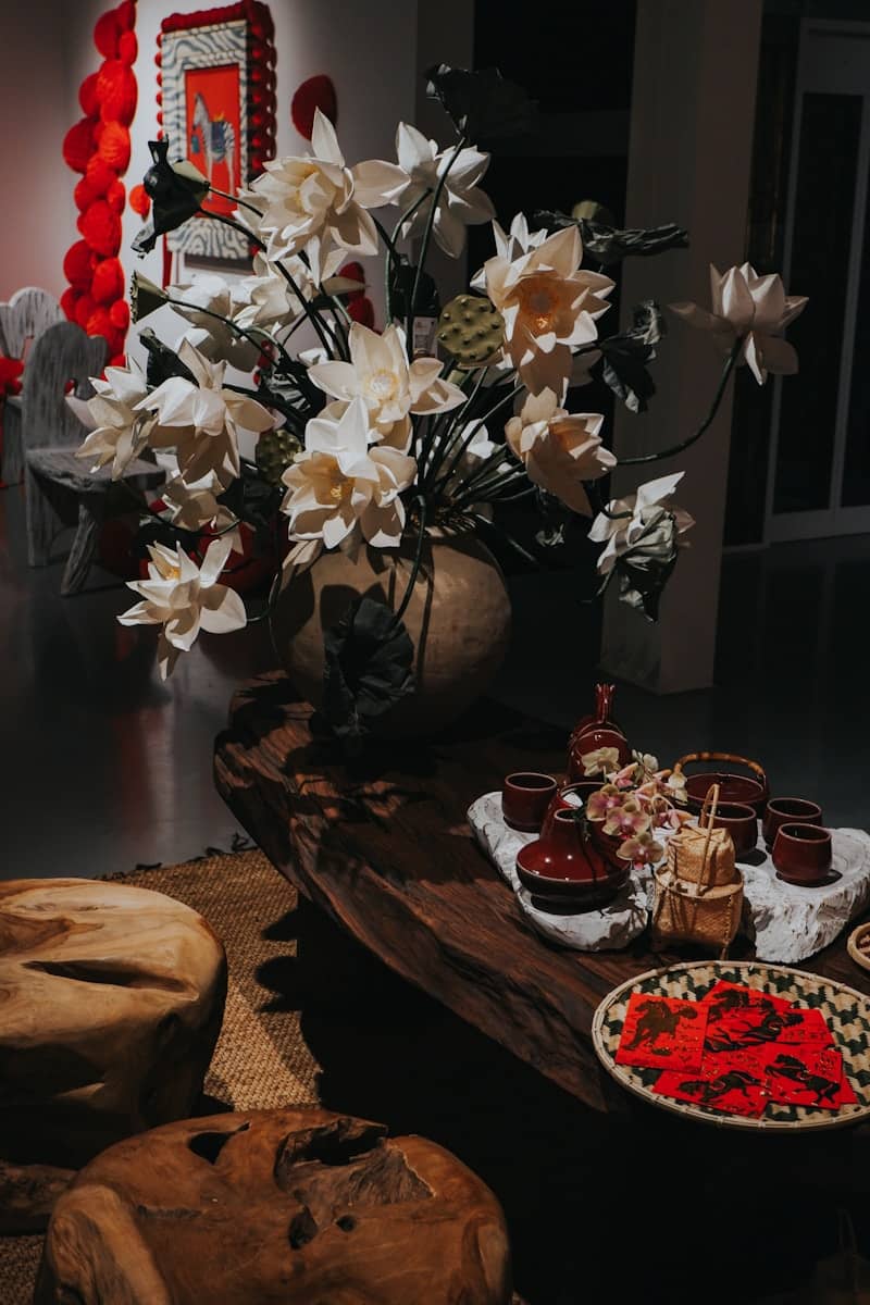 A vase of white flowers sits on a wooden table.