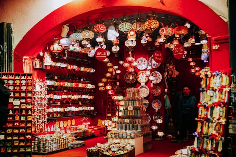 A shop filled with colorful mosaic lamps and decorative plates under a red arched ceiling