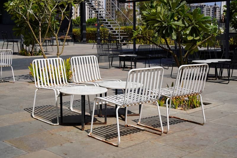 White outdoor chairs and tables on a sunny patio.