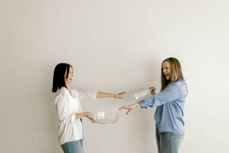 Happy women pouring ingredients into a clear bowl