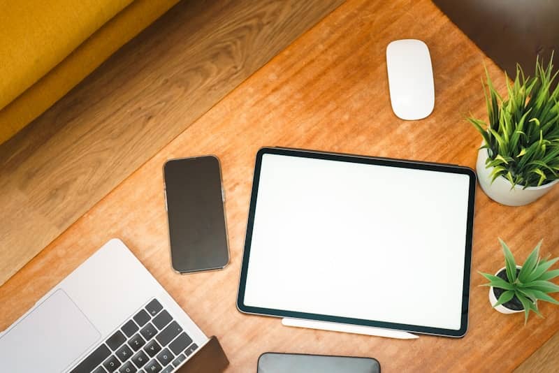 A desk with tablet, phone, and laptop.