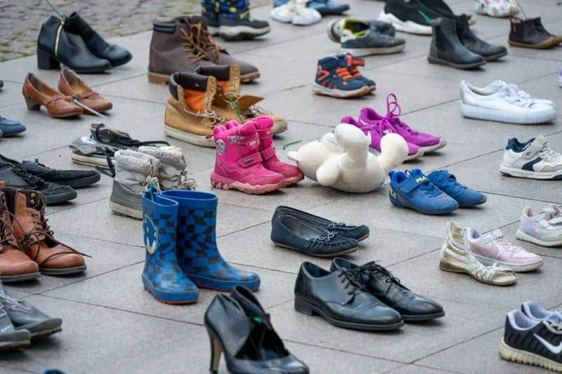 Assortment of various shoes scattered on pavement.