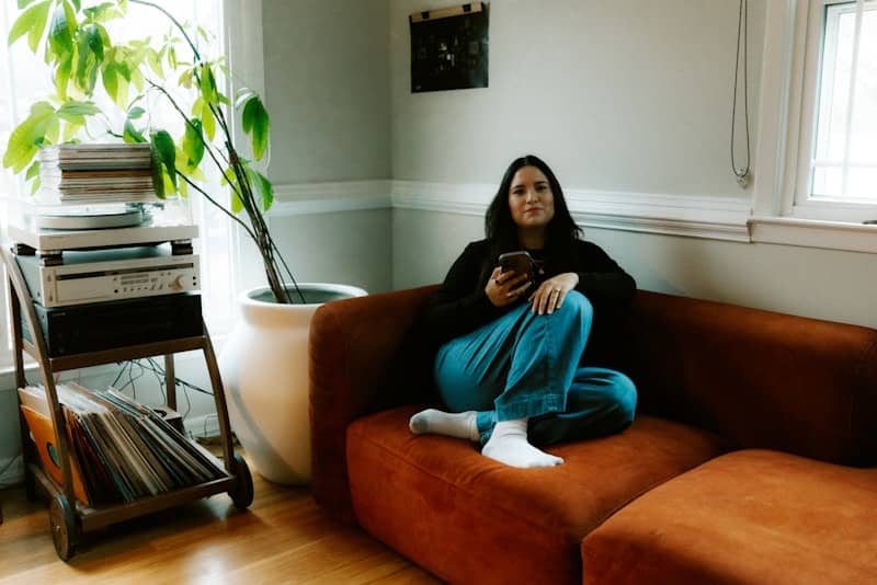 Woman sitting on couch with phone in hand.