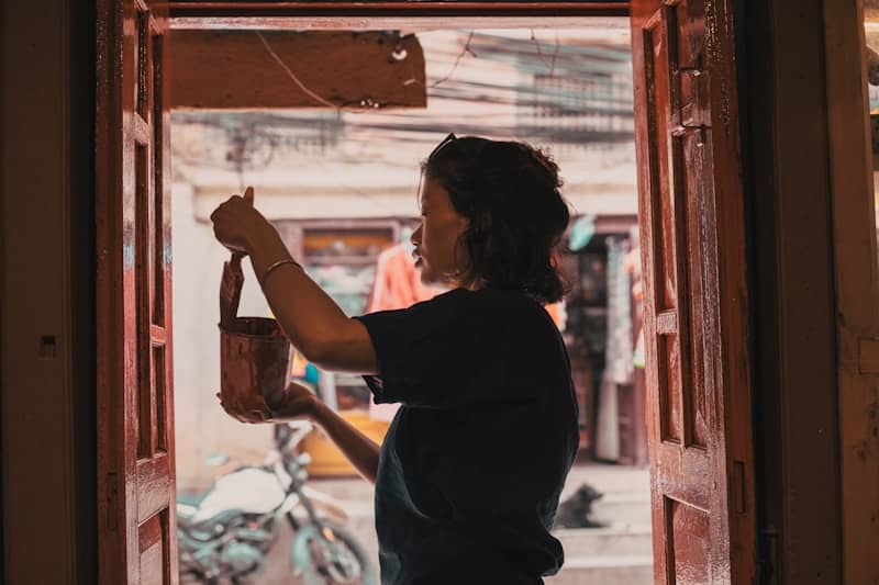 Woman painting front door of apartment