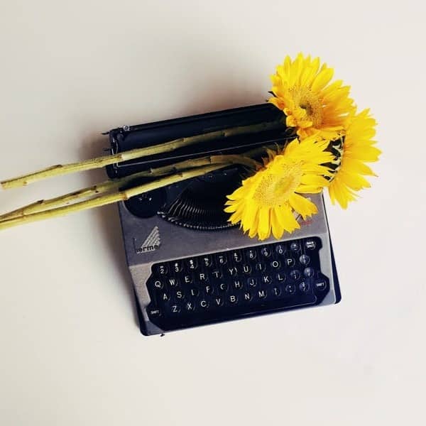 black typewriter with yellow flowers on top