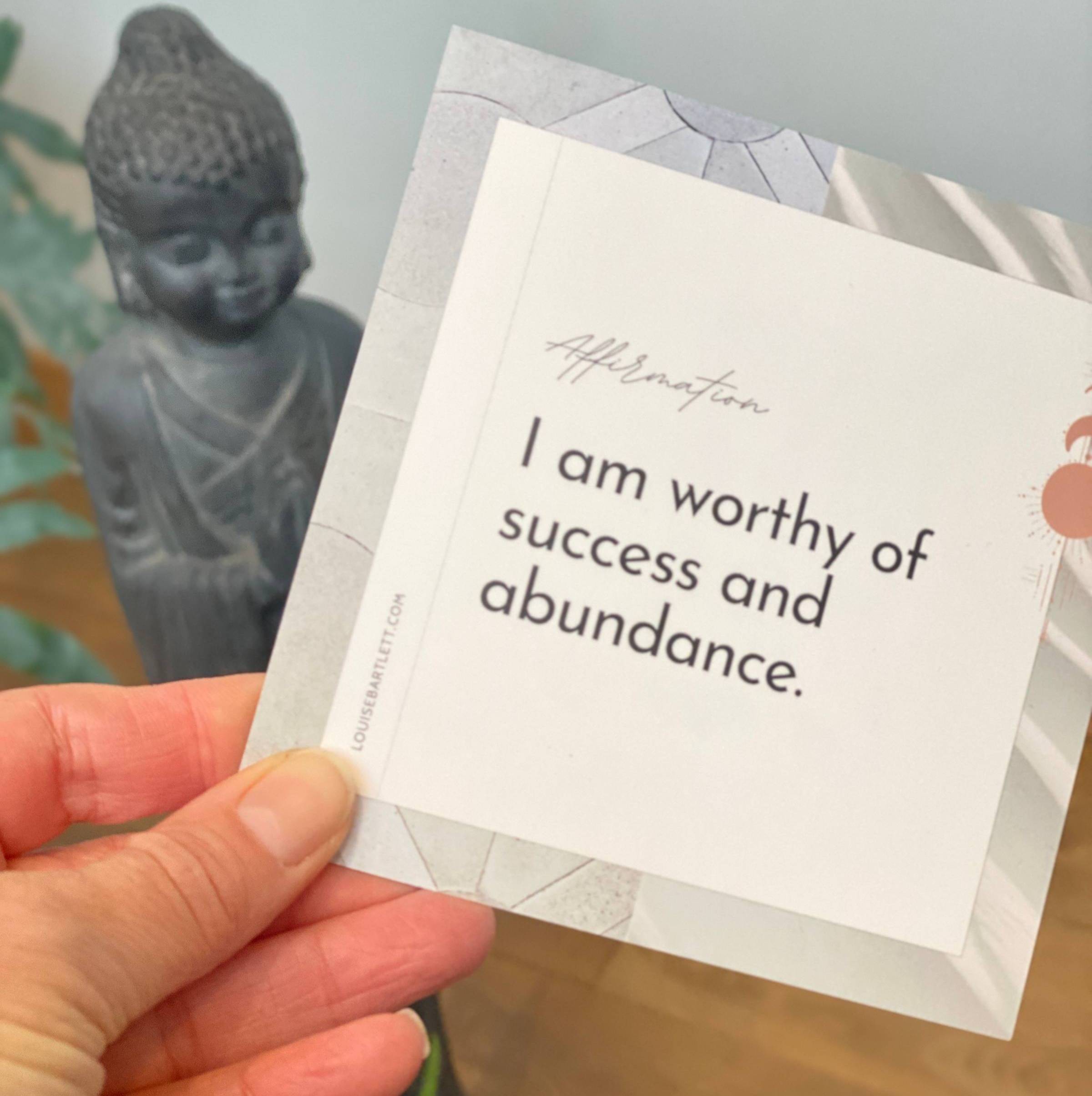 hand holding an affirmation card that reads: I am worthy of success and abundance.