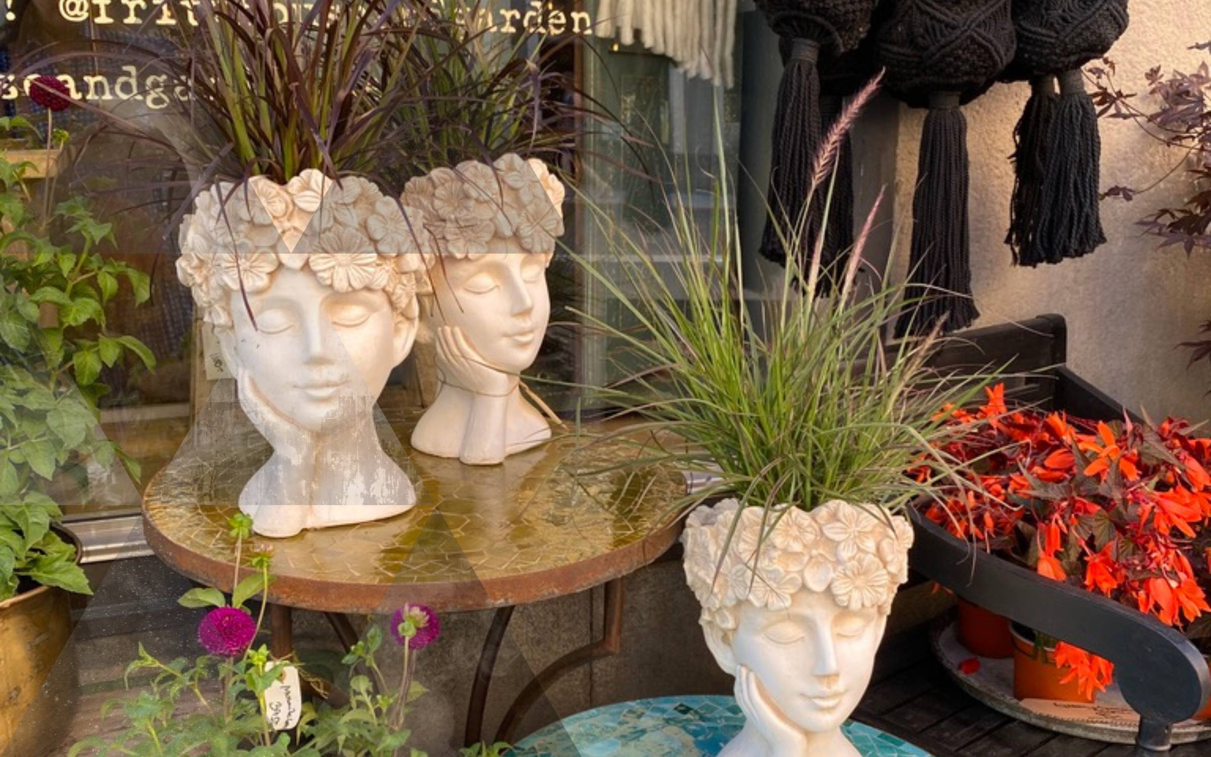 head shaped pots on a table with plants sticking out as hair.
