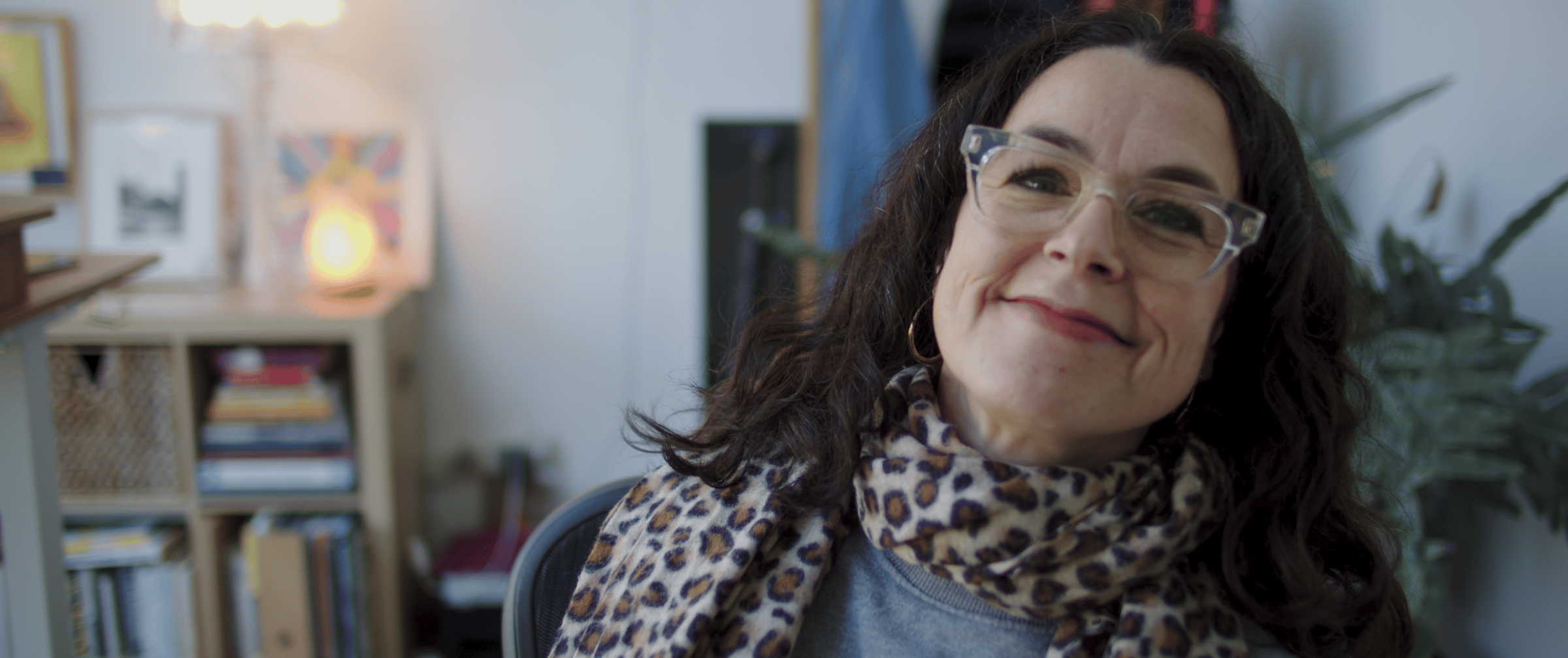 smiling woman with leopard print scarf sitting in a chair