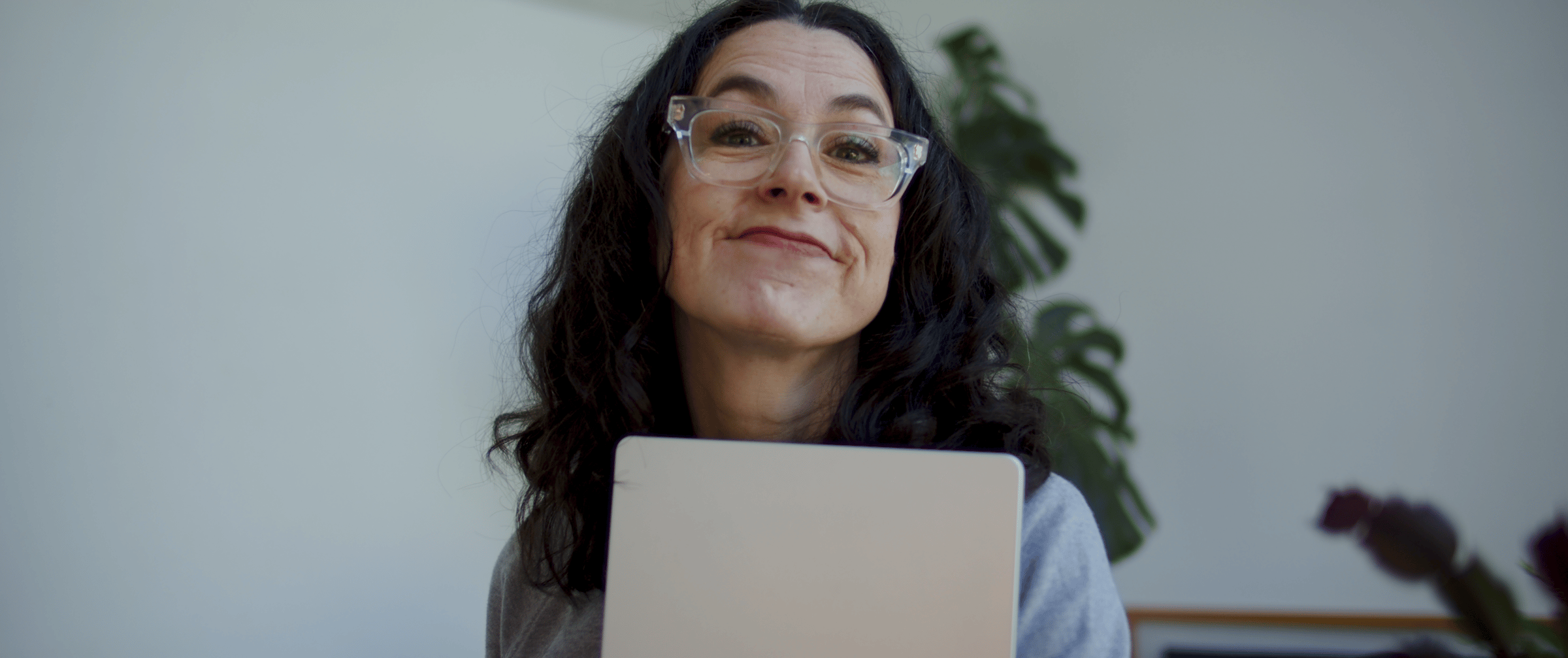 woman with dark hair holding a laptop with slight smile