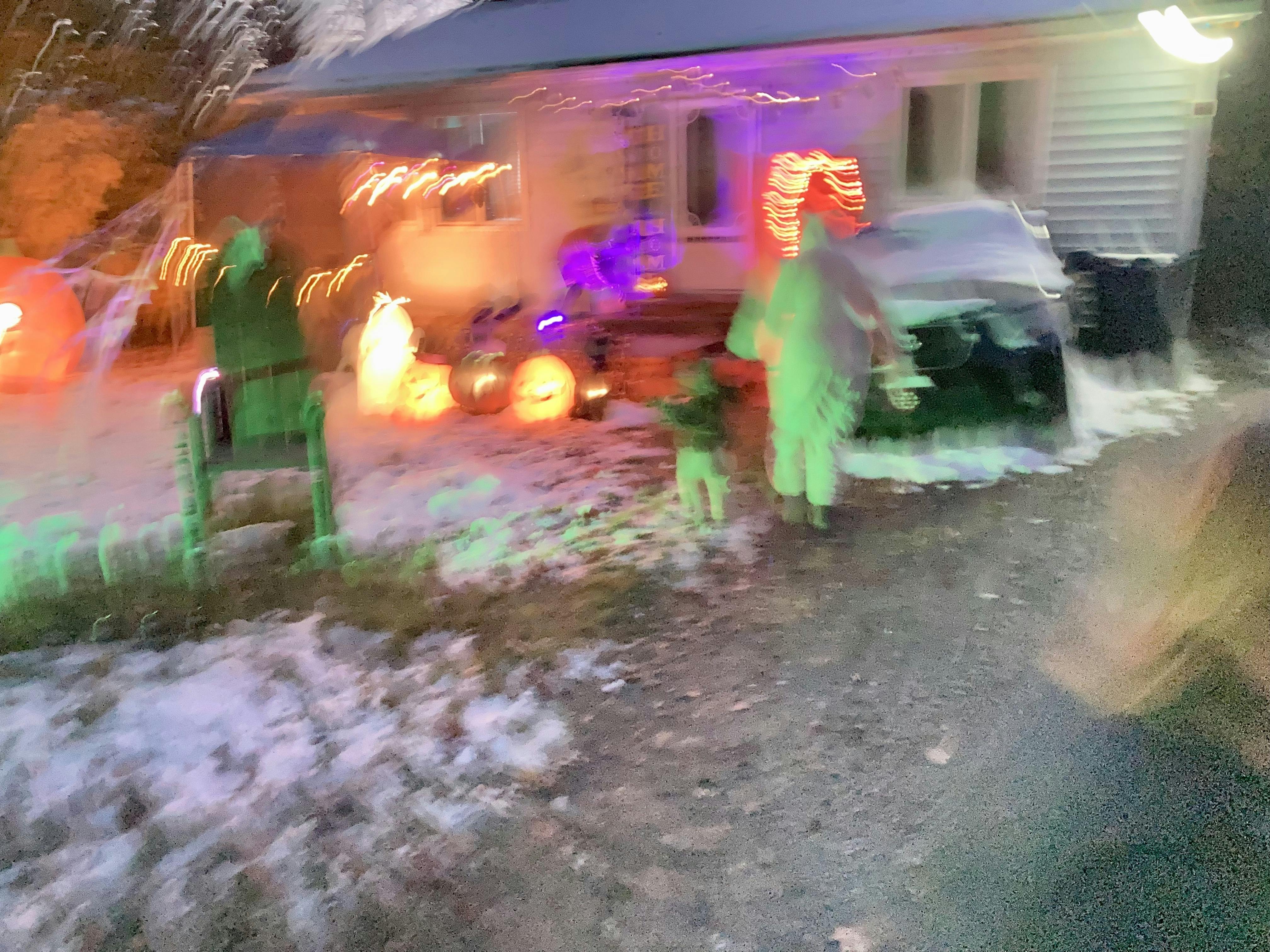 An out of focus photo of a house done up for halloween with trick or treaterss walking toward it.