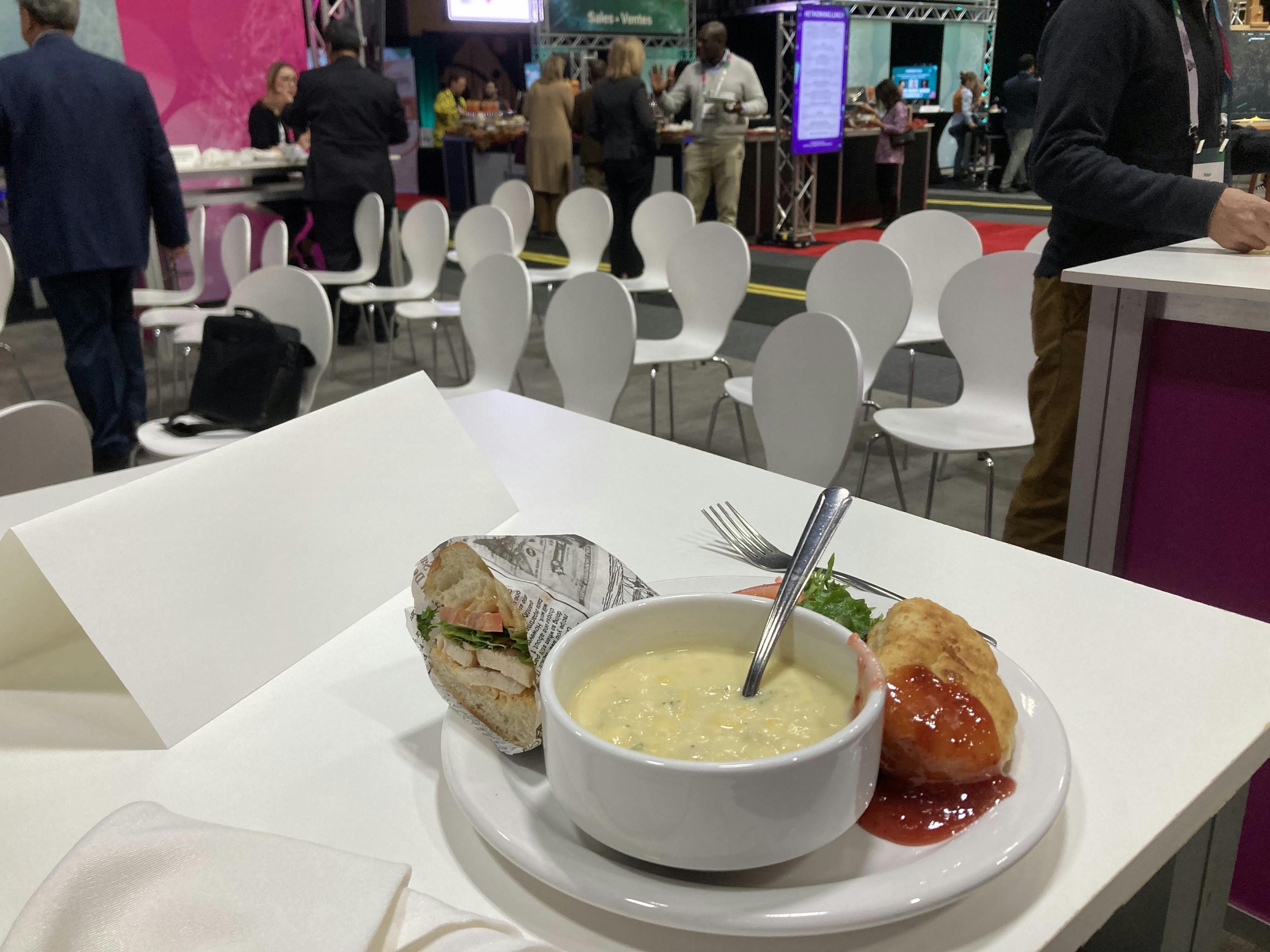 A photo of a plate with soup, a sandwich, and fry bread