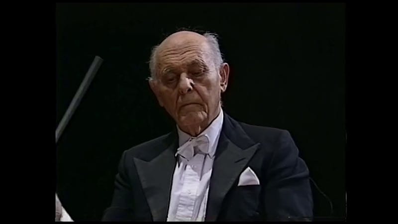 A photo of Sir Georg Solti, wearing a tuxedo and with a conductor's baton in his hand