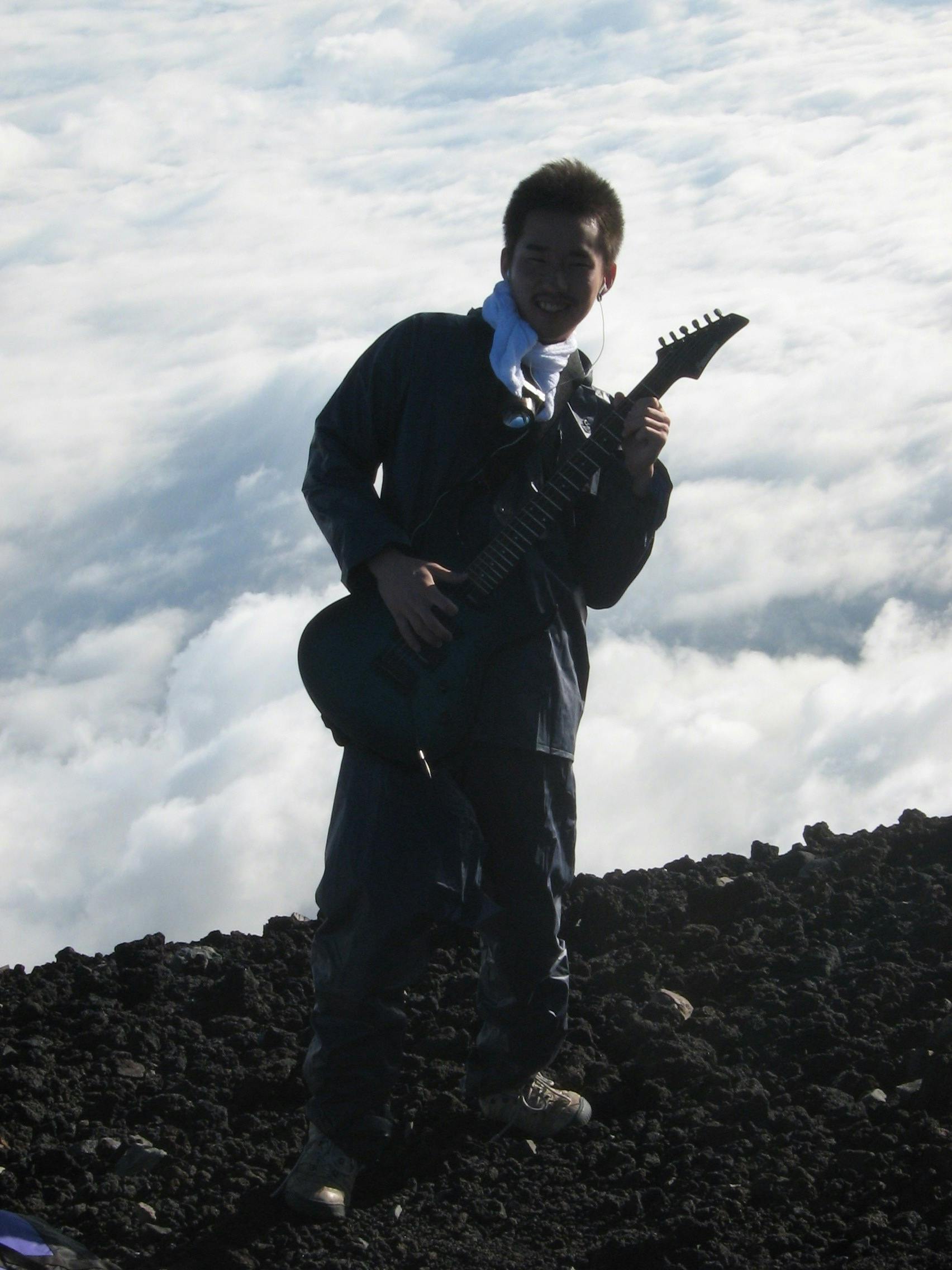 A photo of a guy playing an electric guitar at the top of Mt. Fuji