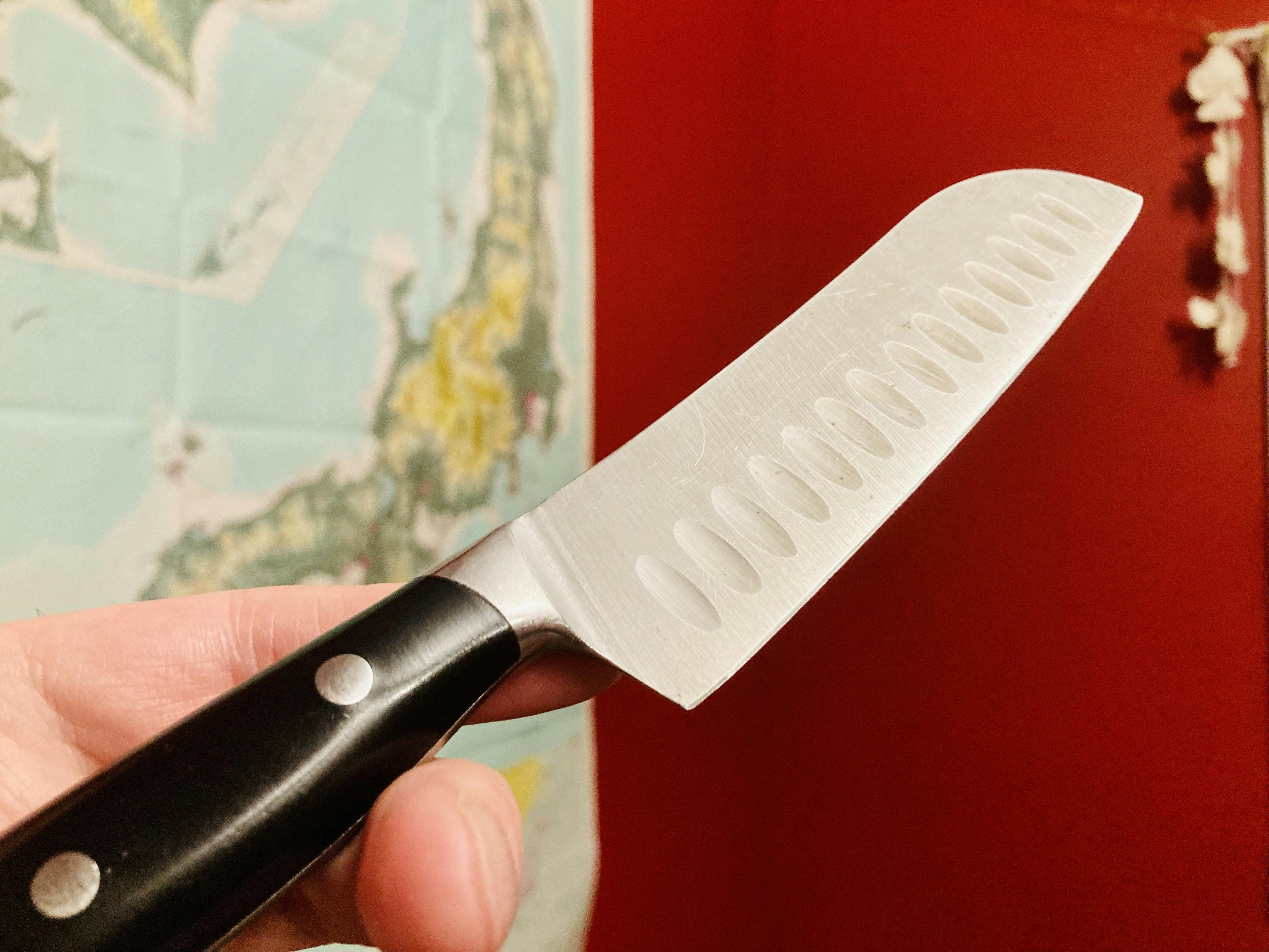 A photo of a plain, santoku-style kitchen knife with a map of Japan in the background.