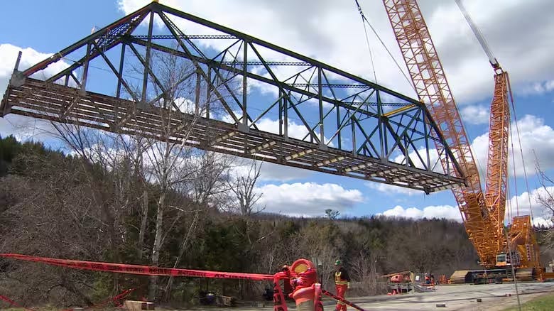 A photo of a crane lifting an entire bridge