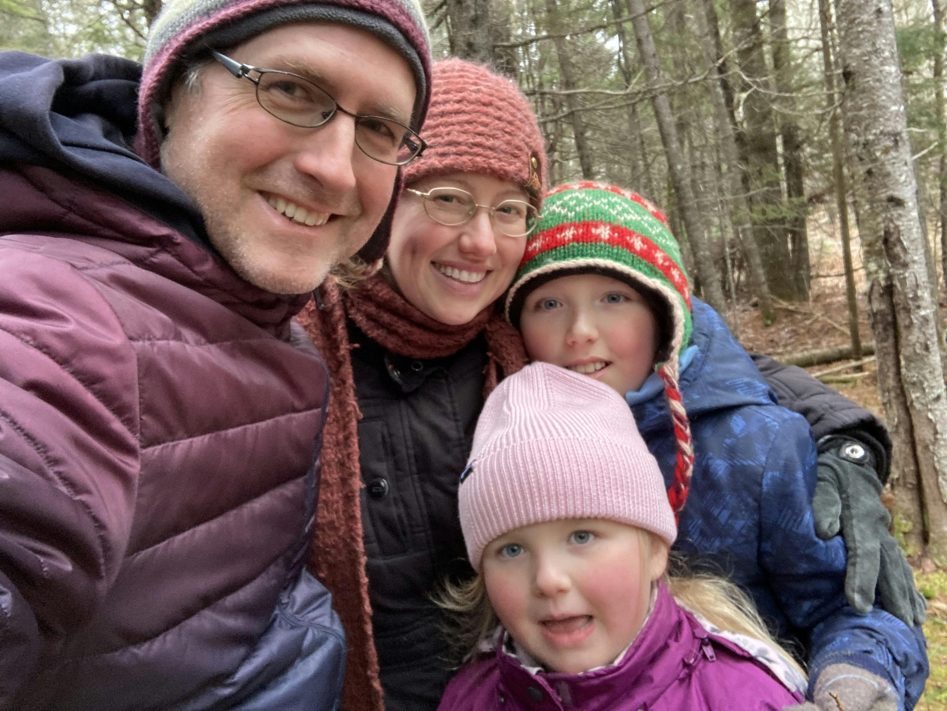 A picture of the Turner family, all wearing winter coats and hats, in the woods - James, Kayte, (Young) James, and Alice