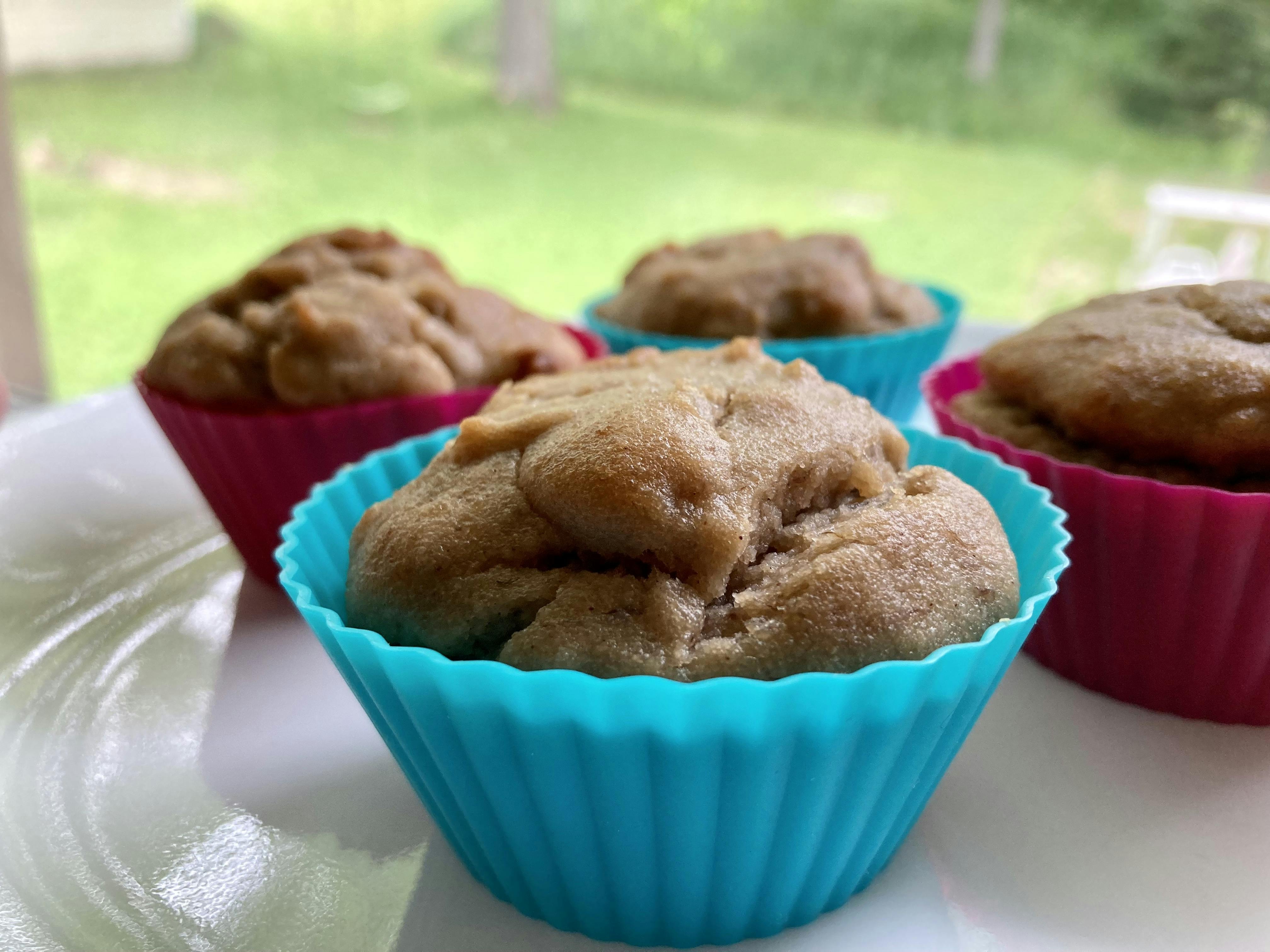 A photo of four, delicious-looking cassave flour banana muffins on a white plate.