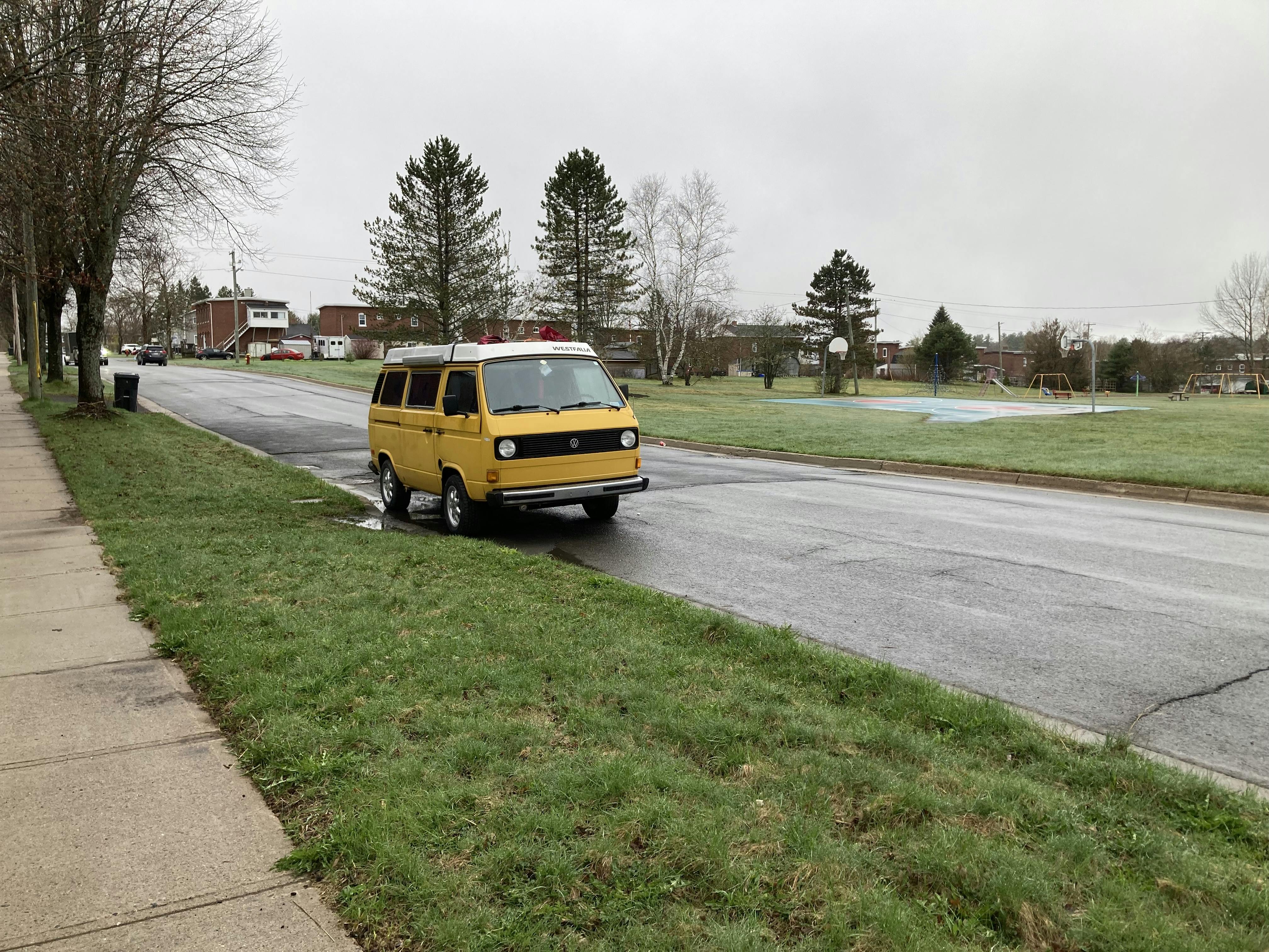 A photo of a yellow Volkswagen T3 Westfalia Camper from the 1980s parked at the side of the street.
