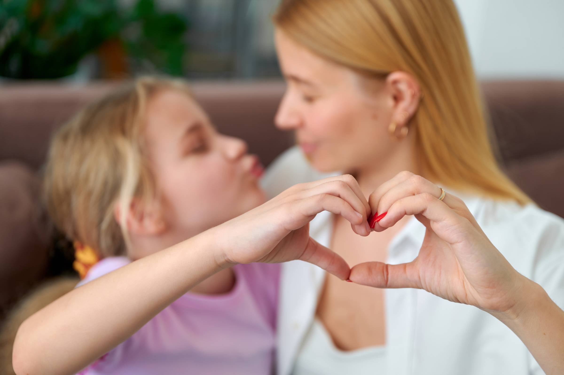 a mother and daughter joining hands in a heart shape