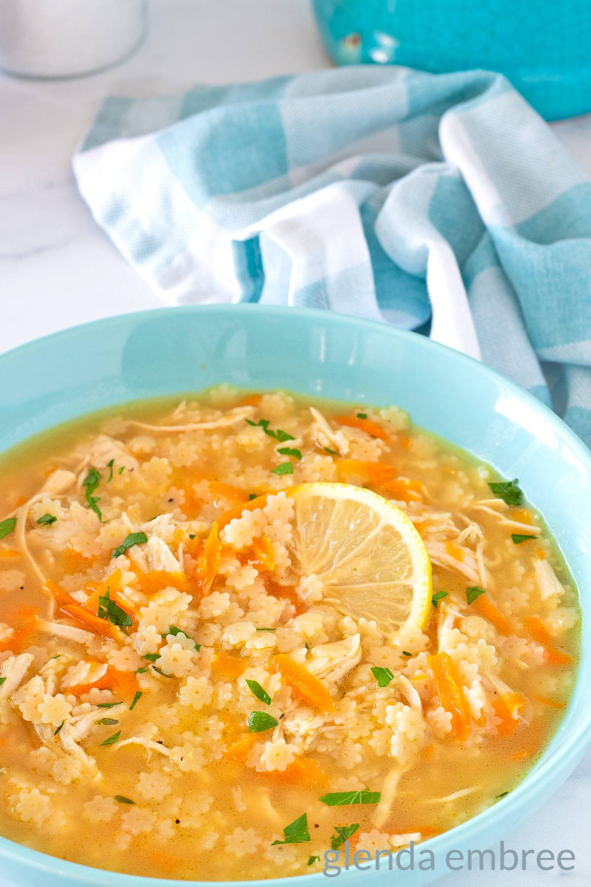 Chicken PAstina Soup in a blue bowl with a lemon slice.