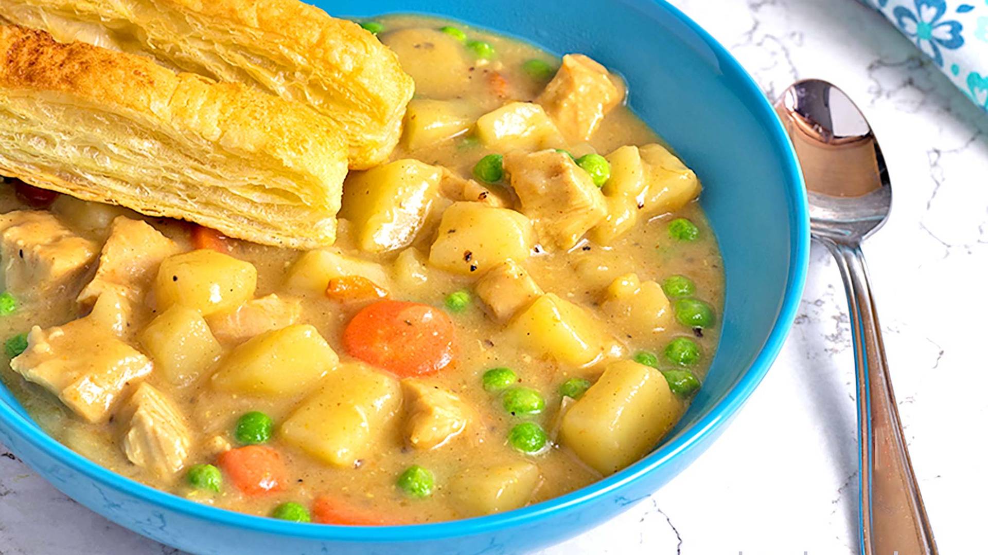 Chicken Pot Pie in a blue ceramic bowl with puff pastry sticks.