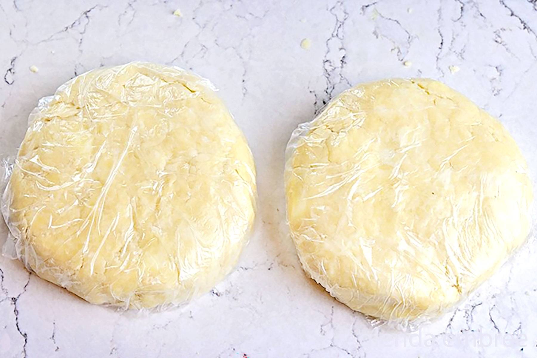 Easy Pie Crust separated into two 4 inch discs and wrapped in plastic wrap for refrigeration or freezing.