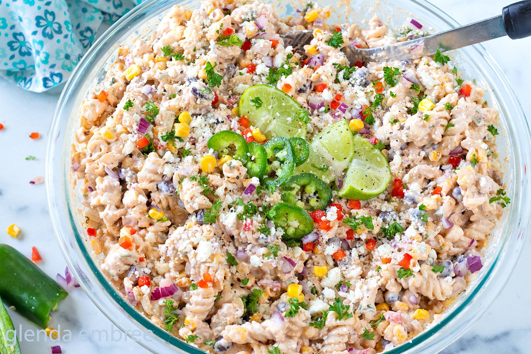 Mexican Street Corn Pasta Salad with Ham in a clear glass serving bowl.