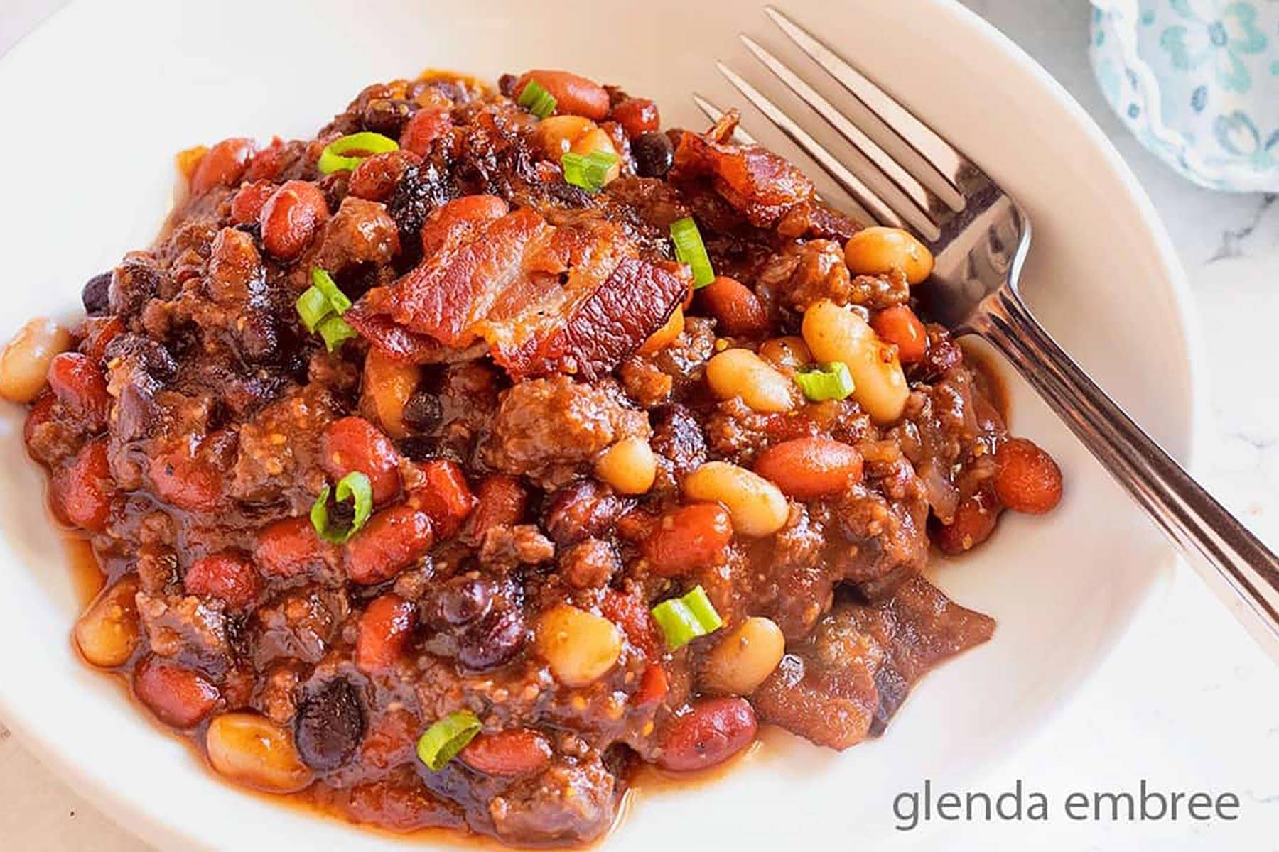 Baked bean casserole in a white ceramic bowl.