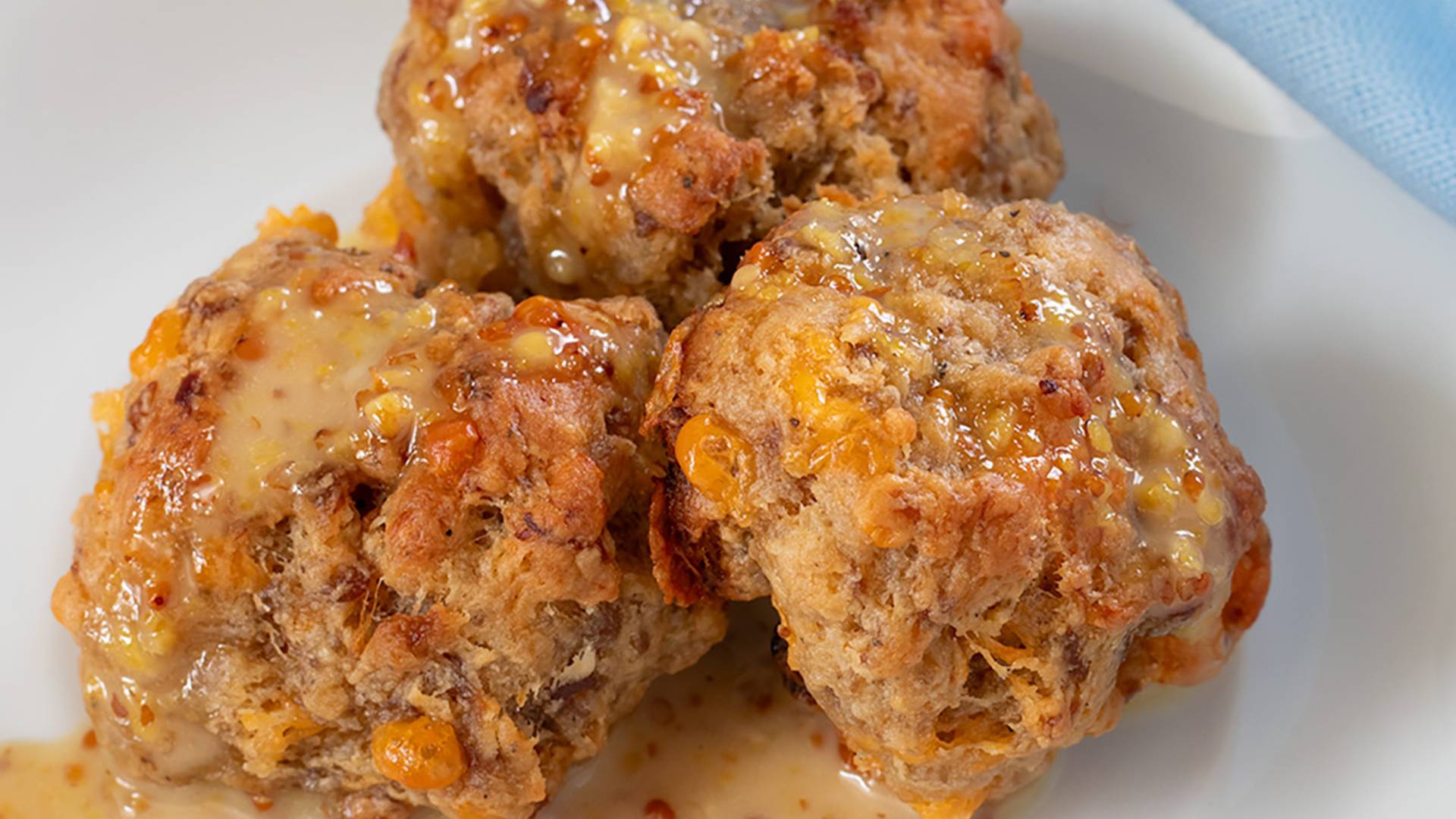 Sausage Balls on a white plate with Honey Mustard sauce.