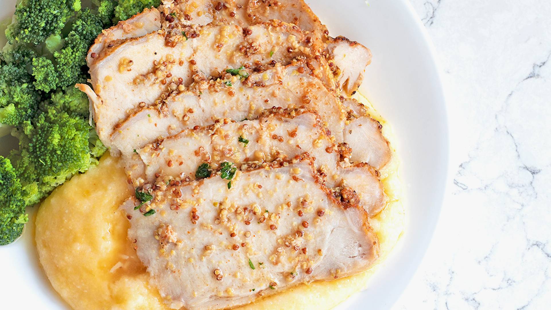 Maple Mustard Pork Loin on a white plate with creamy polenta and broccoli.