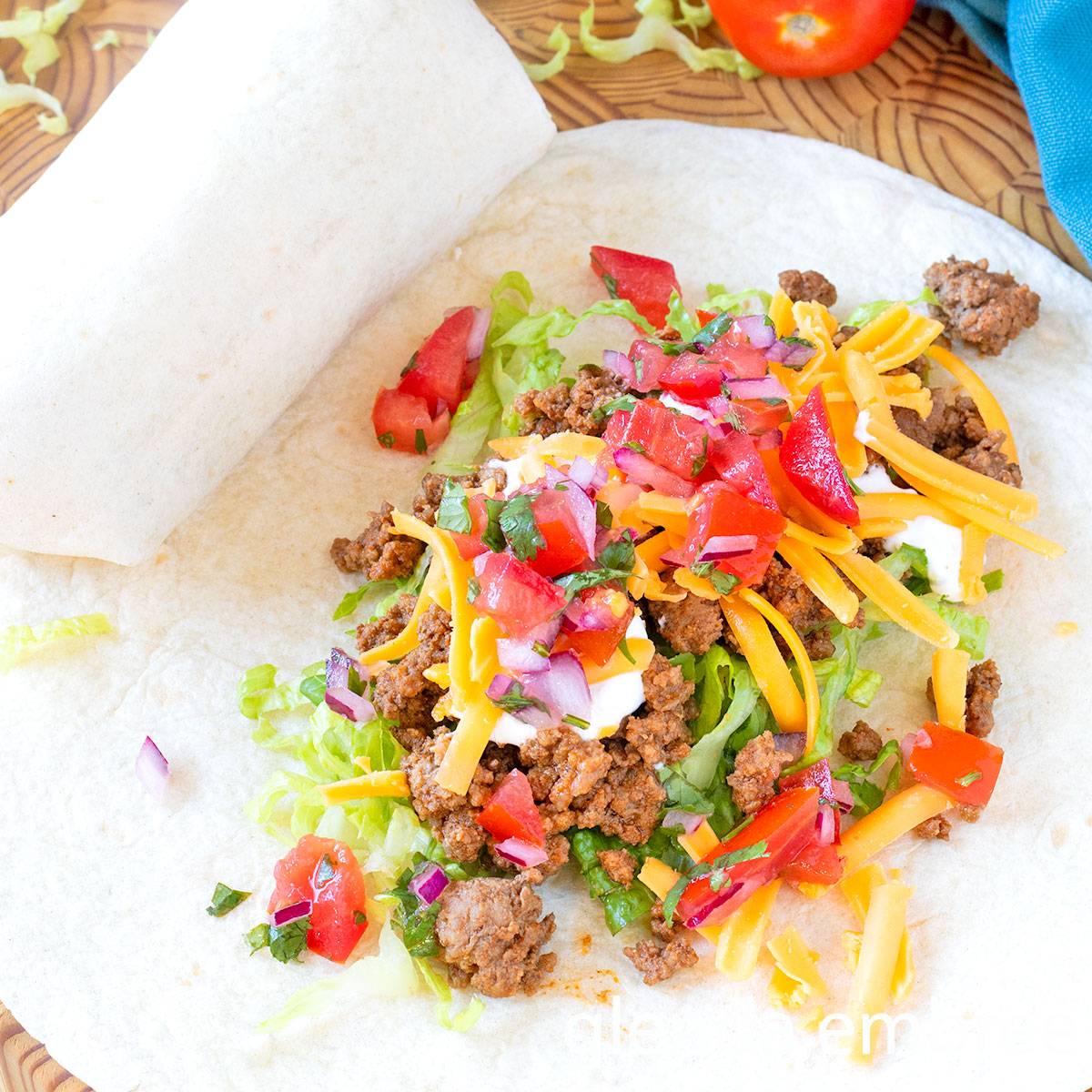 Easy Ground Beef Tacos being assembled on a concrete countertop.