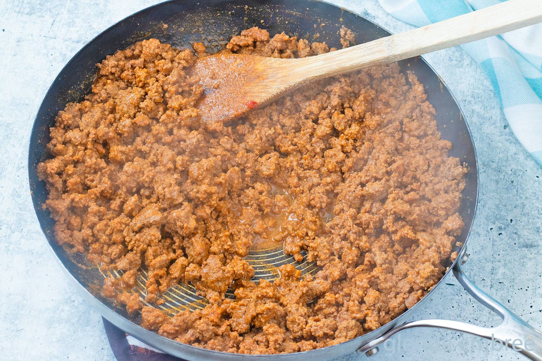 Easy Ground Beef Taco Meat in a skillet with a wooden spoon.