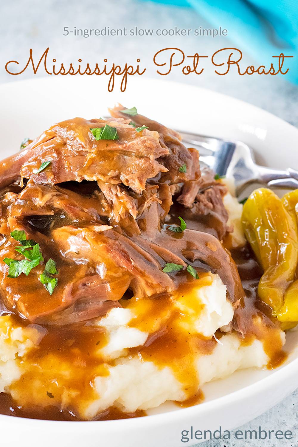 Mississippi Pot Roast over Mashed Potatoes in a white ceramic bowl.