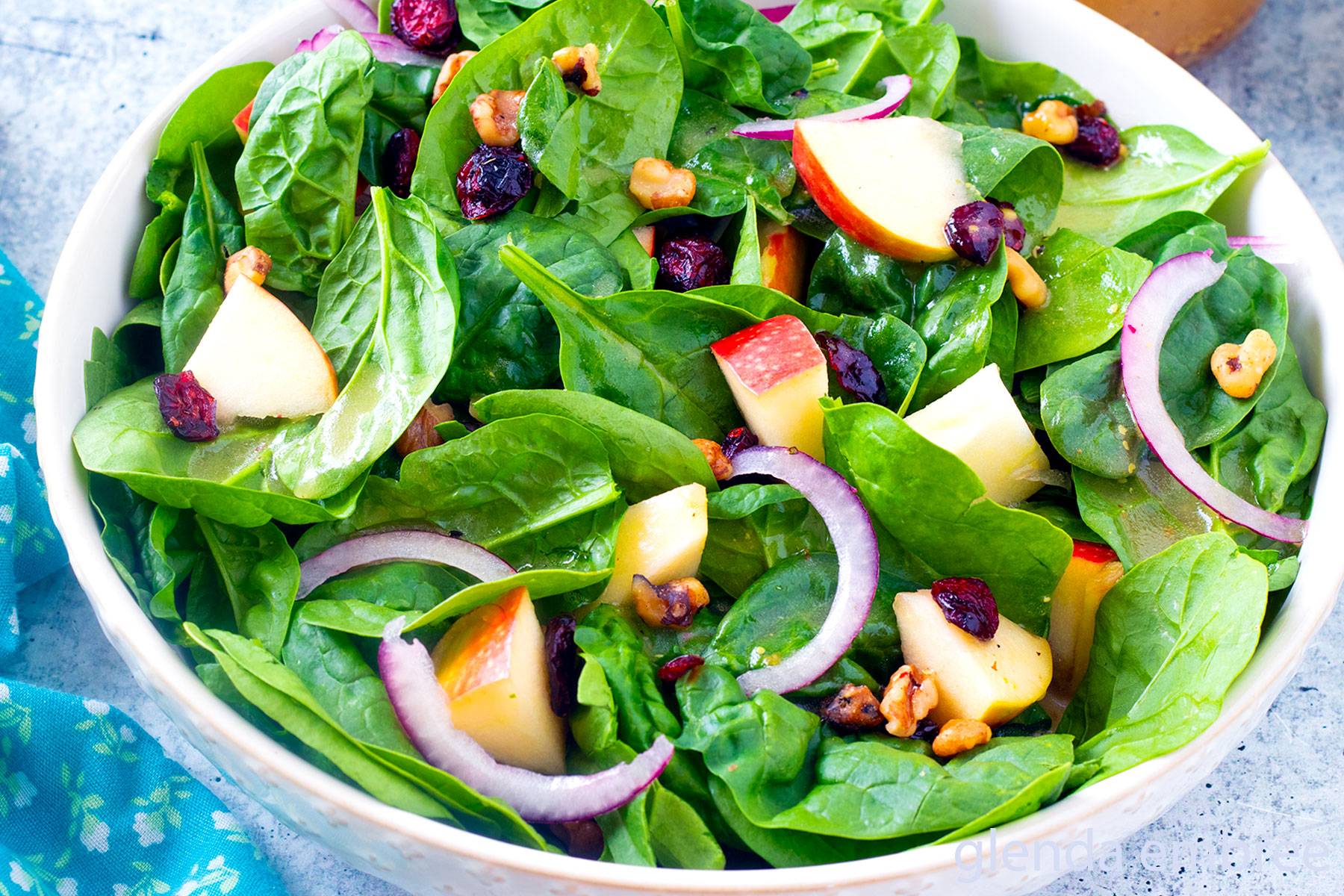 Spinach salad in a white ceramic serving bowl.