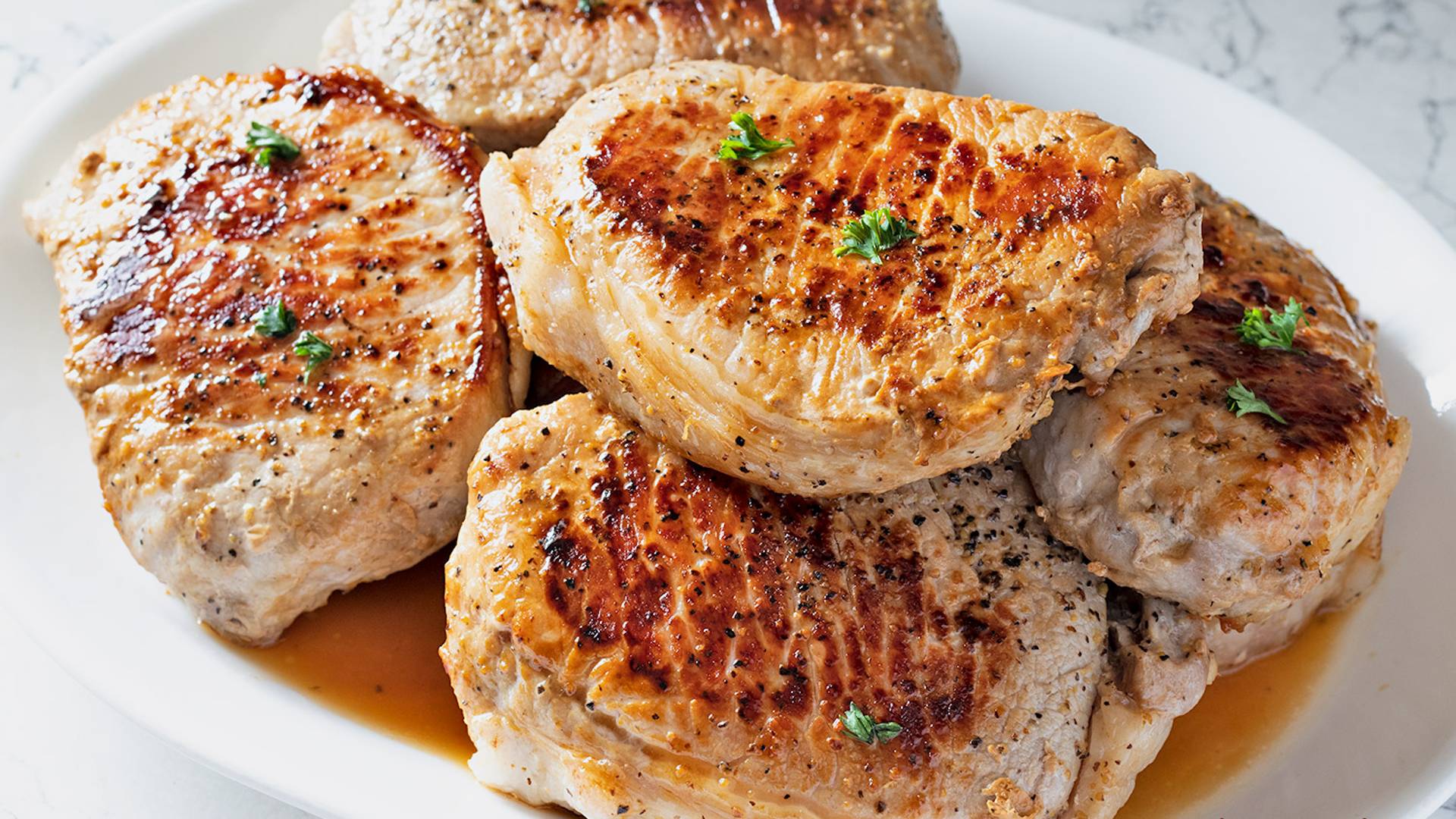Pan seared pork chops on a white platter.