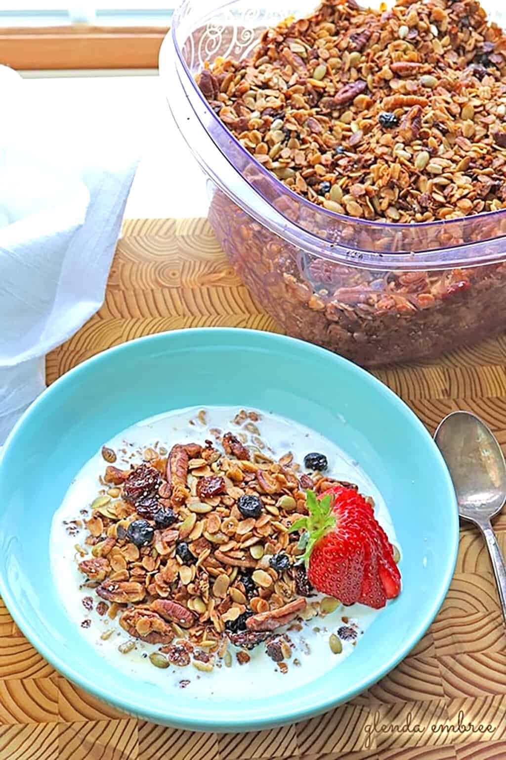 Easy Gluten-Free Granola in a blue bowl with whole milk and sliced strawberries.