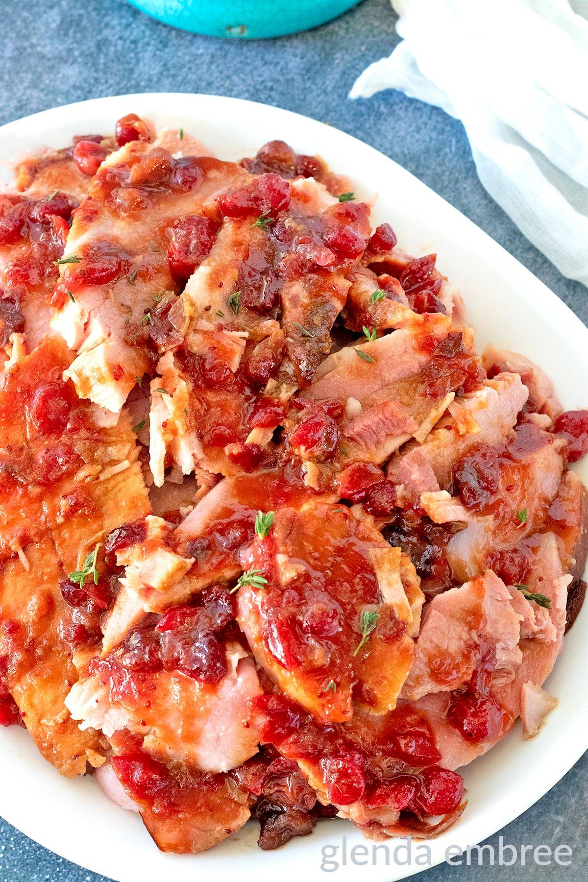 Baked Ham with Cranberry Glaze on a white platter.