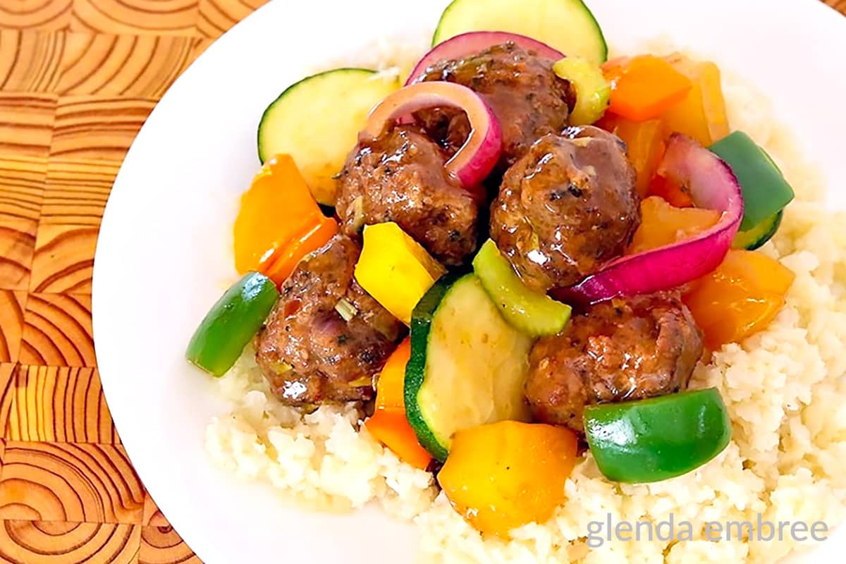 Sweet and Sour Meatballs over Rice on a white plate.