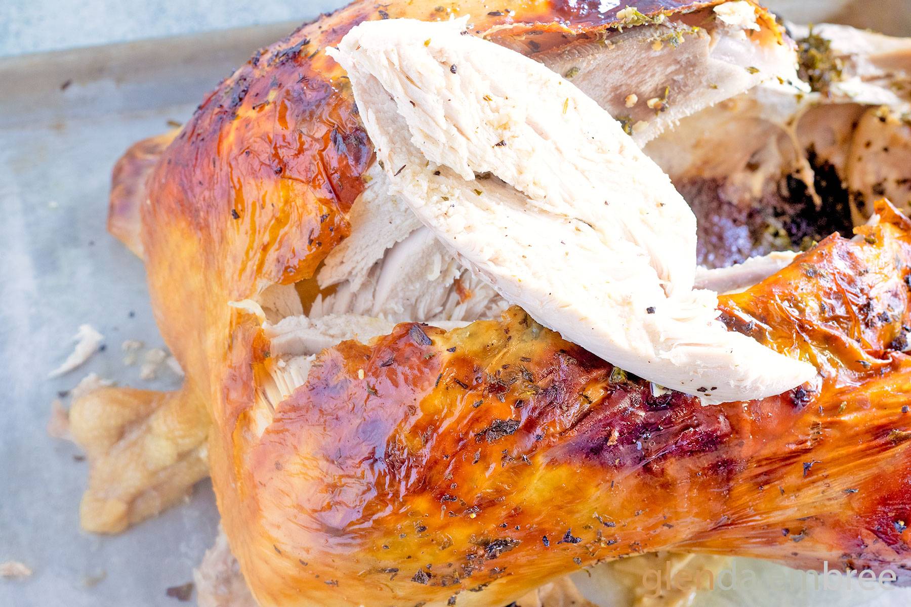 Convection Oven Turkey in a Bag on a baking sheet with the first slice removed from the turkey breast.