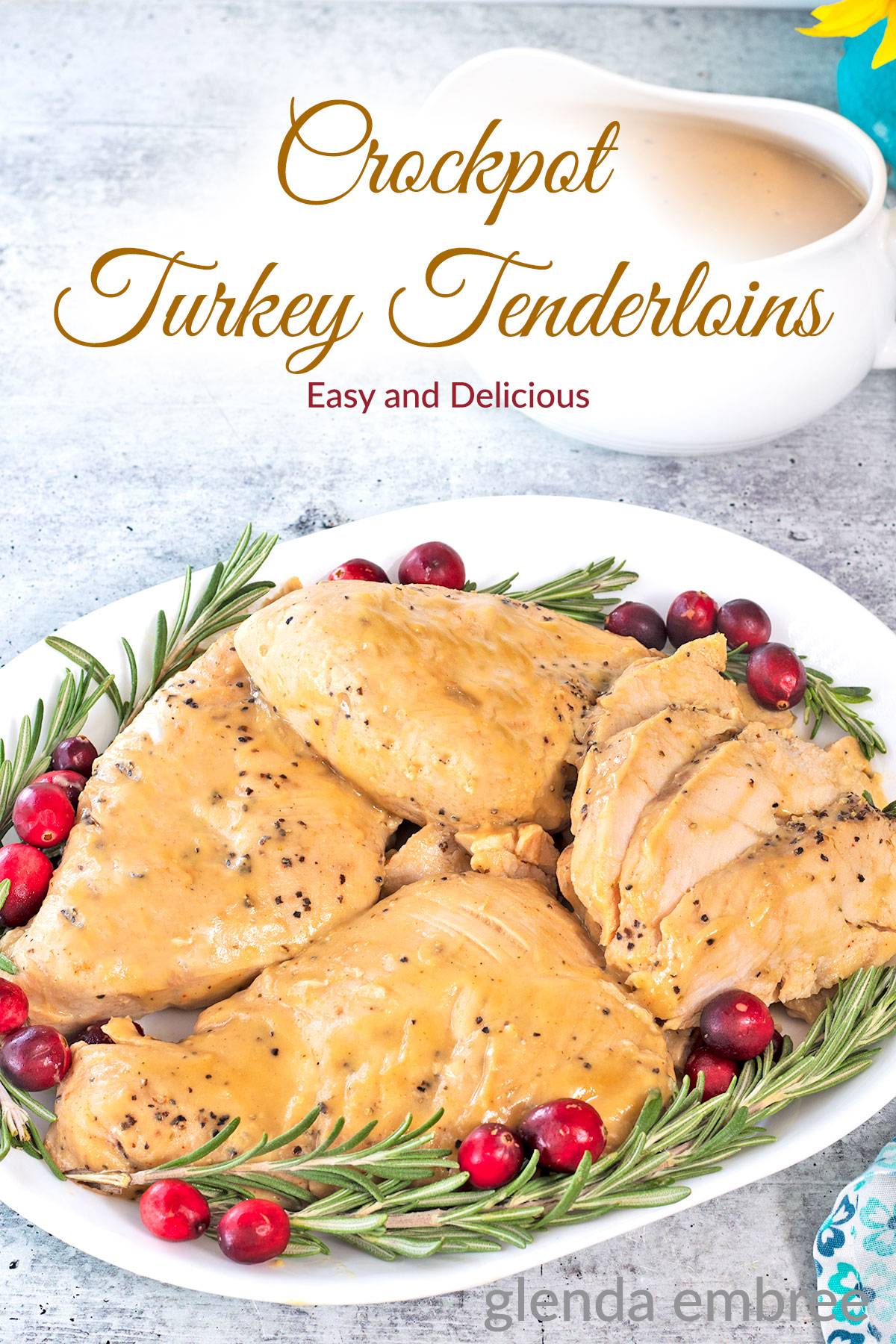 Crock Pot Turkey Tenderloins on a white platter with rosemary sprigs and cranberries.