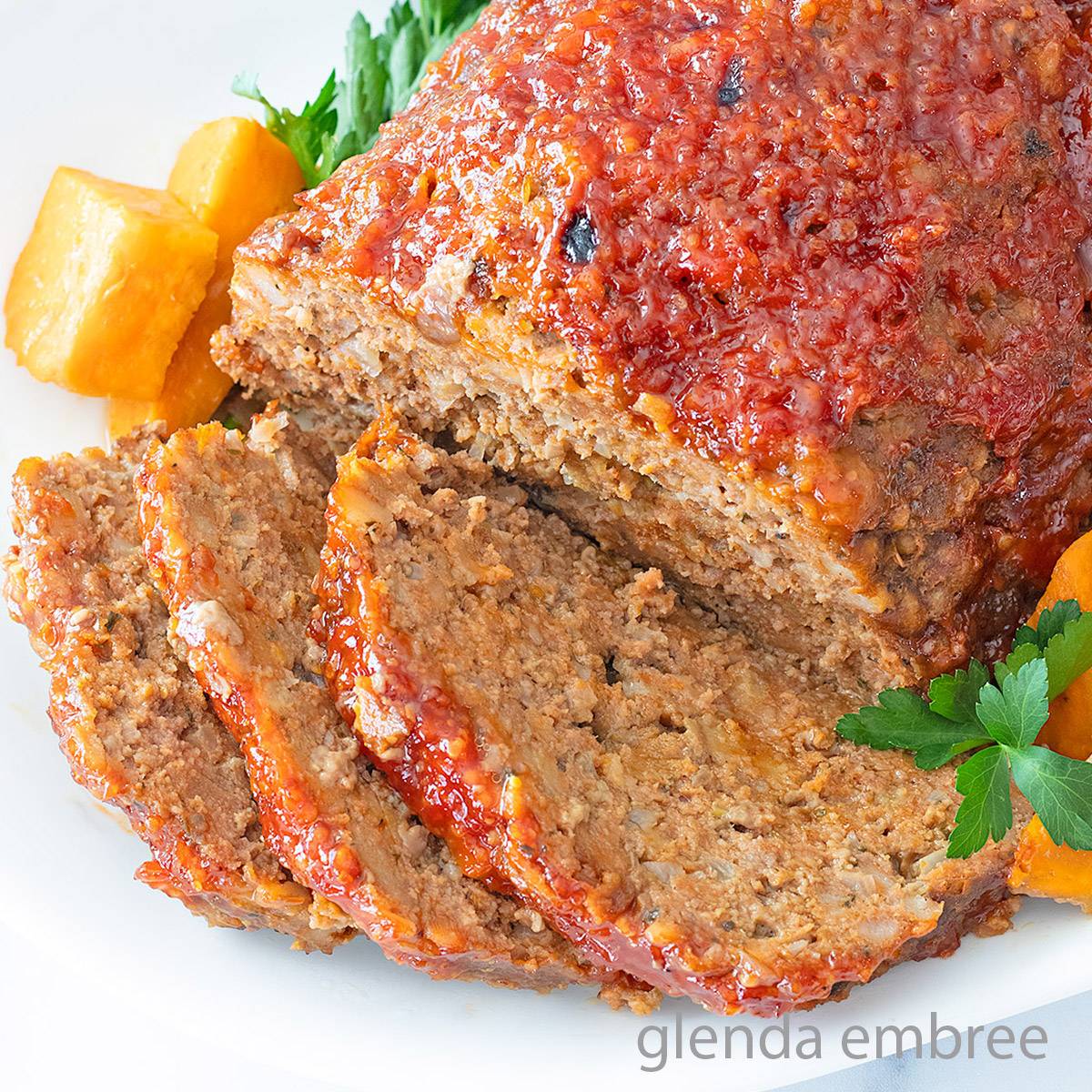 Stove Top Stuffing Meatloaf on a white platter with chunks of roasted sweet potato and fresh parsley.