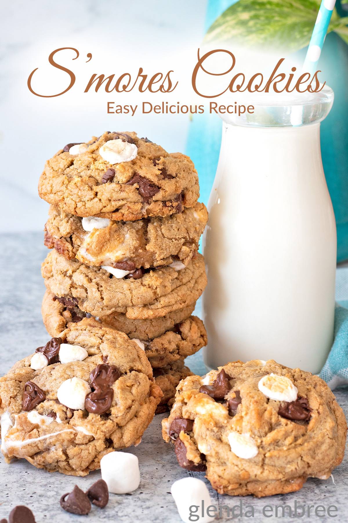 S'mores cookies stacked next to a bottle of milk on a concrete countertop.