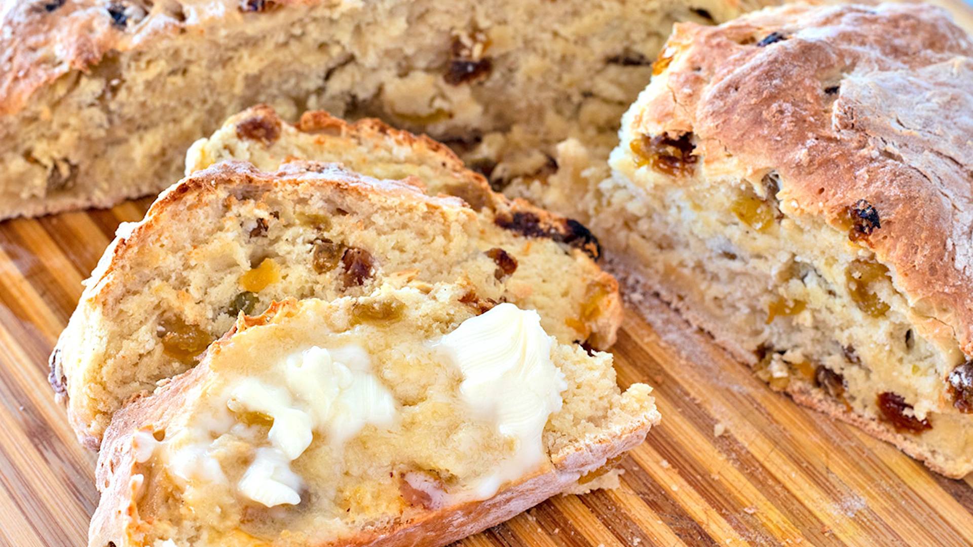 Buttered Soda Bread slices on a wooden cutting board next to the loaf they were sliced from.