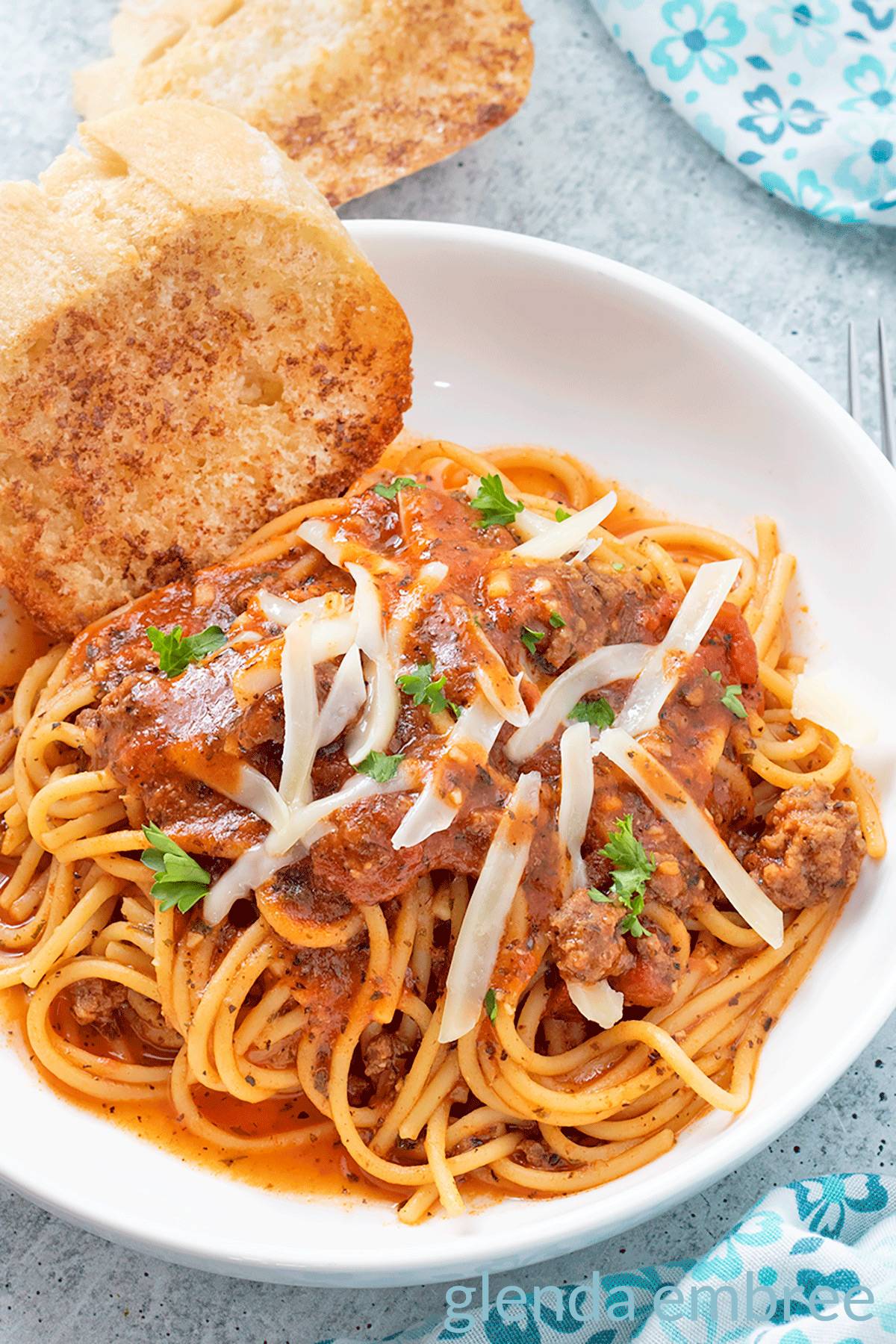 Easy spaghetti in a white pasta bowl with garlic toast.