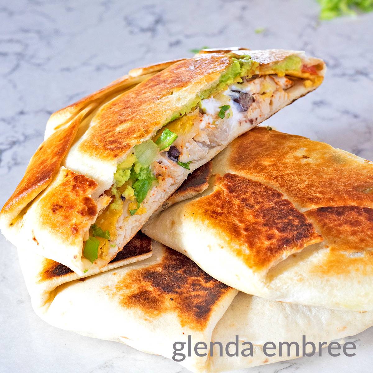 Chicken Crunchwrap Supreme cut and sections stacked on a marble countertop.