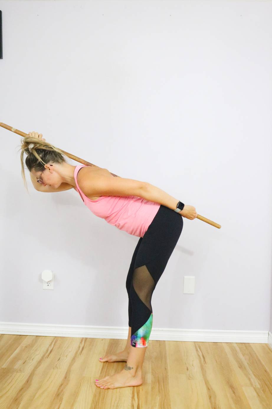 Woman performing a hip hinge with a dowel.