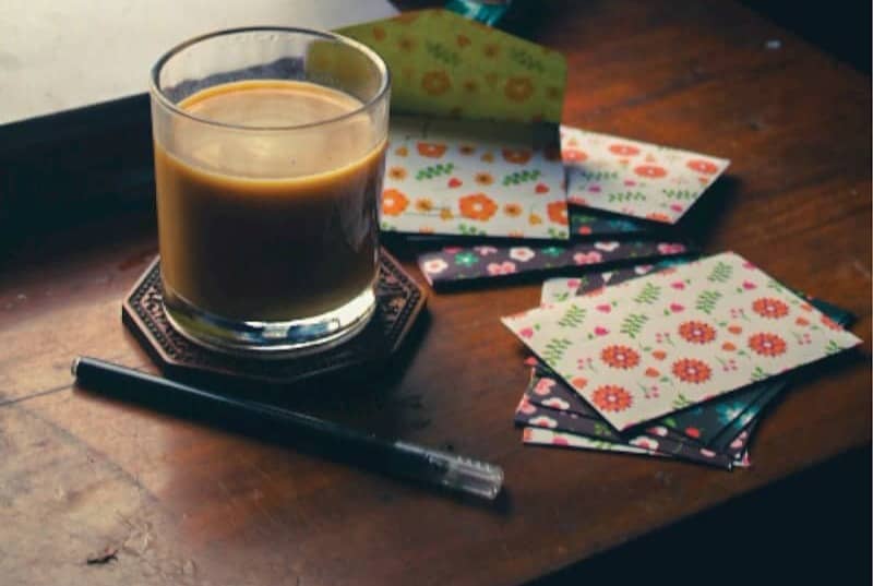 A glass of coffee sits on a wooden desk.