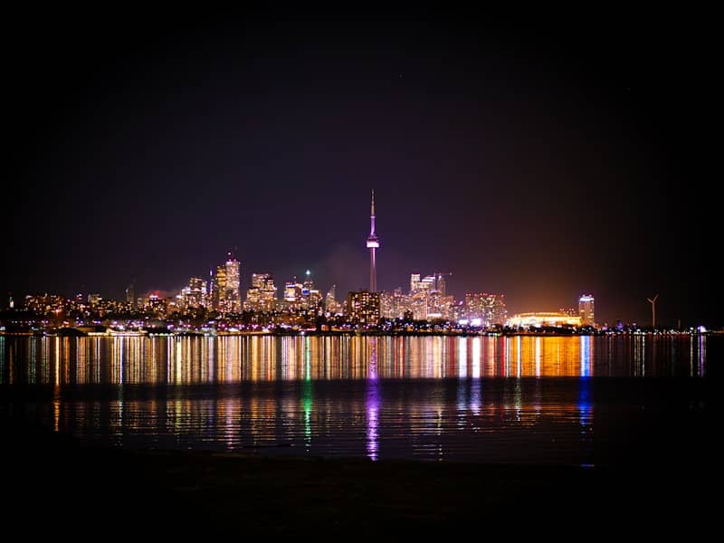 City skyline at night with colorful lights reflected on water
