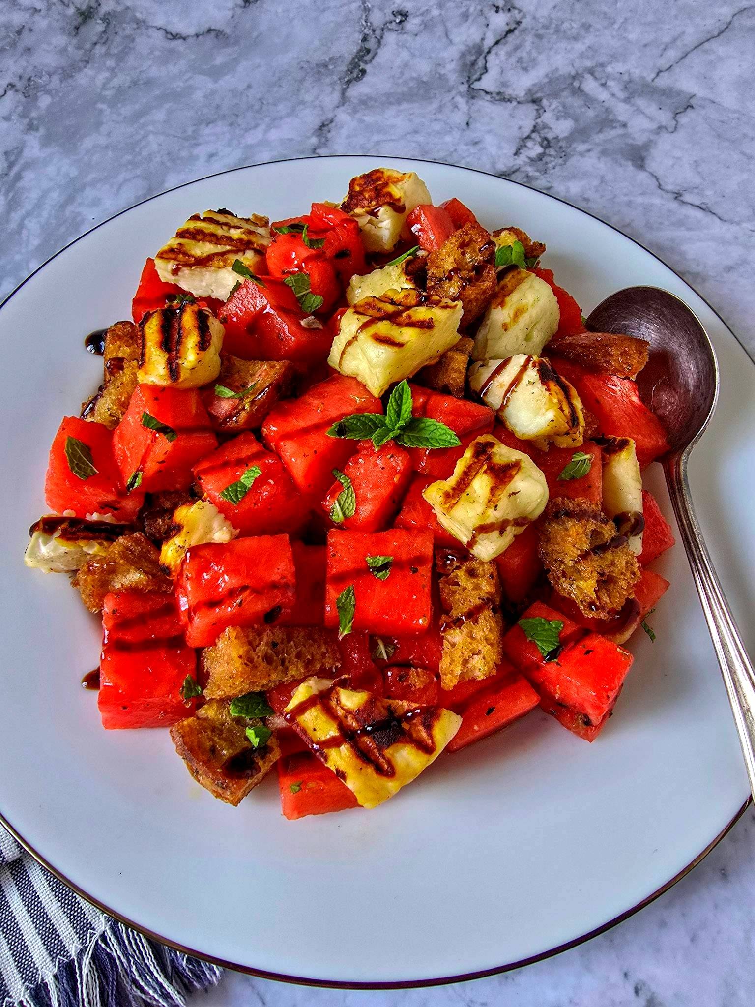 Watermelon and grilled halloumi salad with sourdough croutons, fresh mint, and a balsamic drizzle