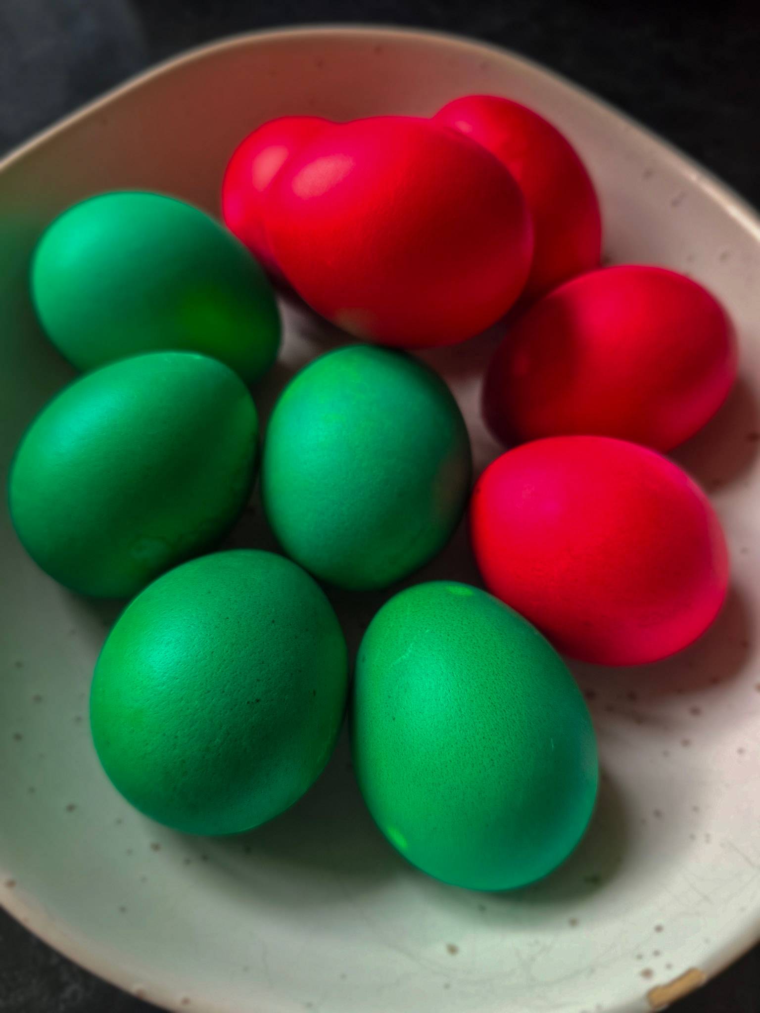 Painted red and green Easter eggs in a bowl.